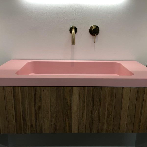 Meubel met wasbak. Wasbak in roze kleur en het meubel gemaakt van hout.