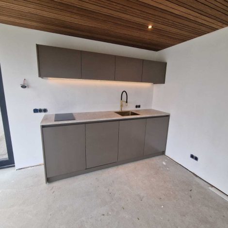 Keuken in tuinkamer met kookplaat, koelkast, vaatwasser en legplank met led verlichting